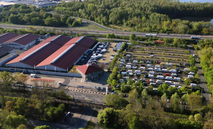 Drohnenaufnahme aus der Vogelperspektive auf das FUNK.CAMP an der Messe Kassel: Zahlreiche Wohnmobile von Funkamateuren stehen auf einem Parkplatz. 
