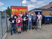 Gruppenbild der Teilnehmenden mit Urkunde vor DLRG Schild