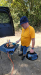Grillmeister am Kugelgrill, darauf Würstchen