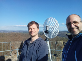 Tim und Wolfgang oben auf dem Rehbergturm vor einem WLAN-Spiegel